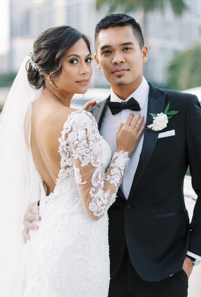 Bride in white lace dress long sleeve embracing groom in black tux