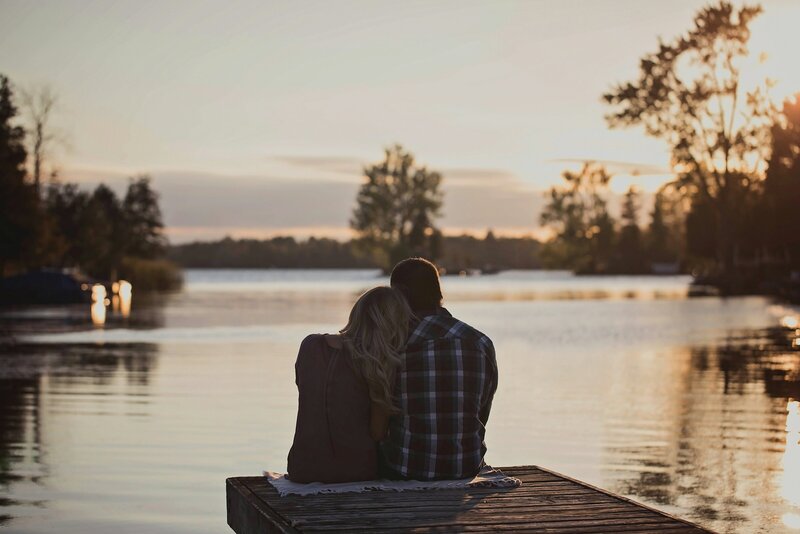 Couple sitting on a dock at sunset, embracing and looking over a lake – representing relationship support and couples counselling with Freedom Couple Counselling in Melbourne.