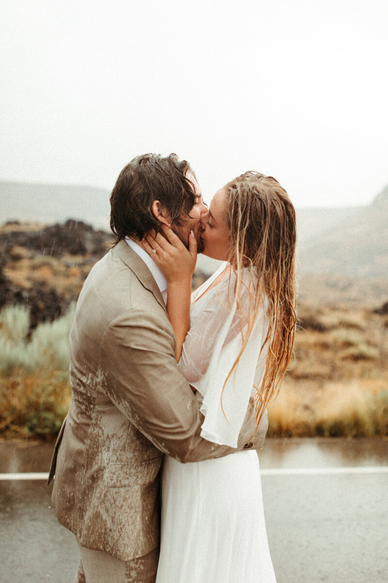 Boho bride and groom hugging on mountain top in Georgia