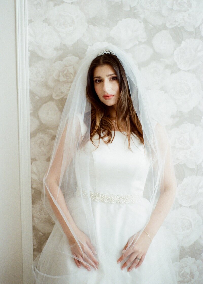 Bride poses against a wall captured by a film camera.
