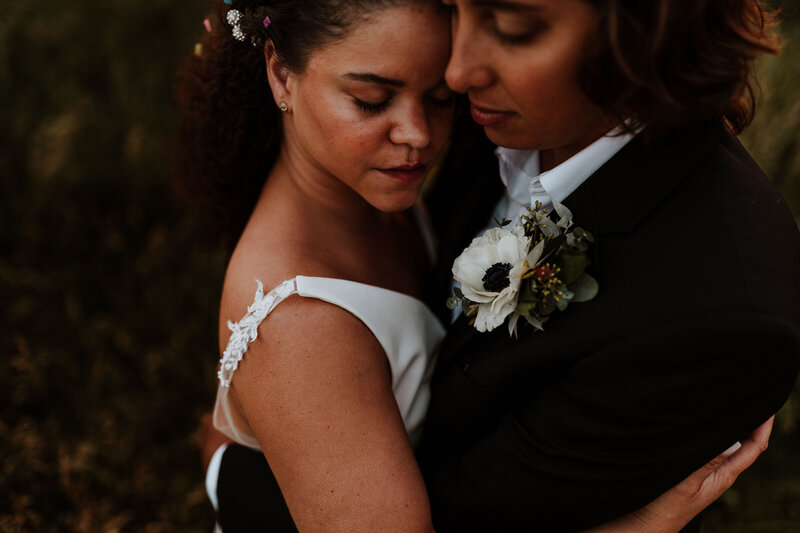 Two brides embracing during sunset.