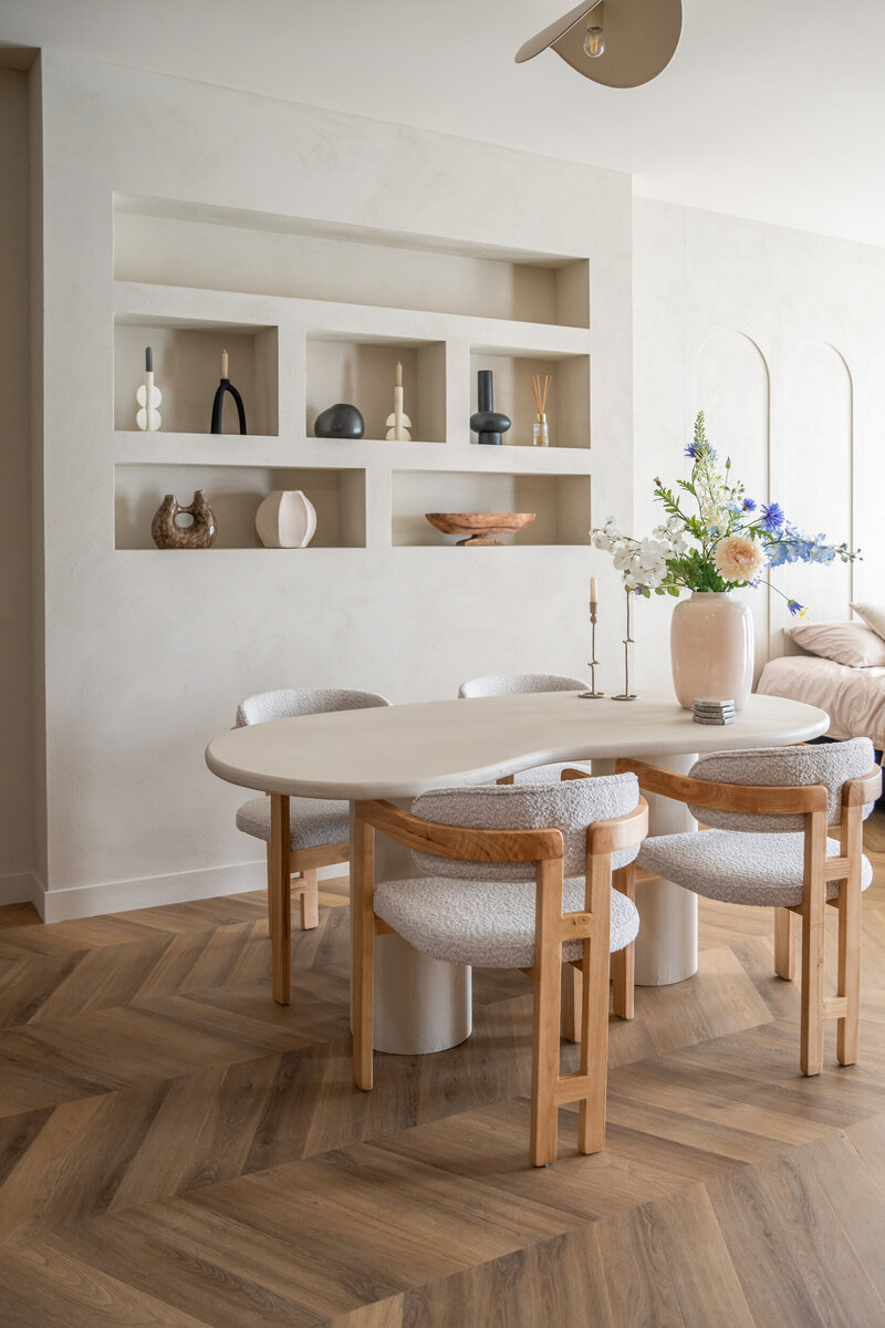 Organische tafel met vier designstoelen en vakkenkast