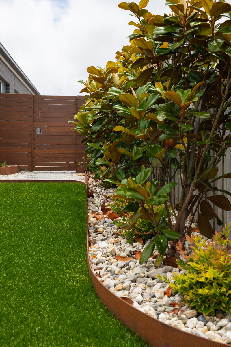 Sleek landscape design with garden bed edging and synthetic grass
