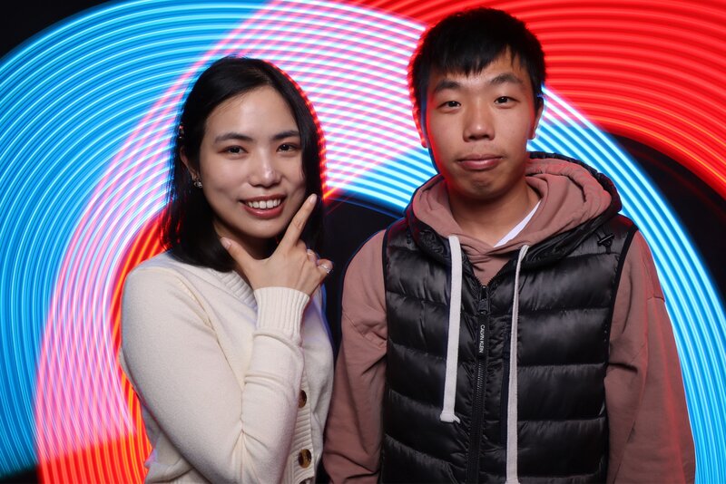 Two guests posing in front of a vibrant red, blue, and white light trail backdrop created by MISGIF’s light painting photo booth, ideal for immersive corporate events and brand activations in Phoenix, Arizona