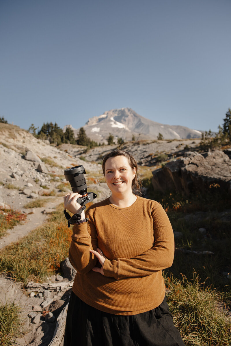 Family Photographer standing by a wooden fence and smiling at a park in Oregon