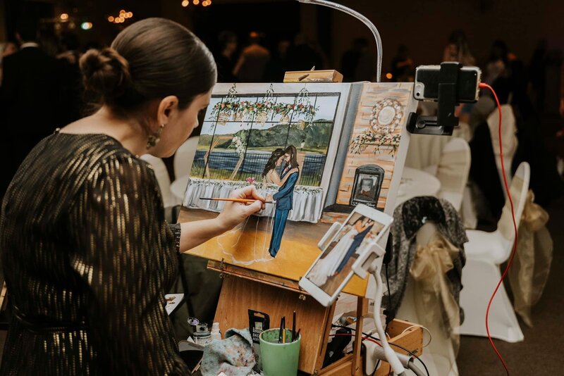 A behind the scenes style photograph of Debbie working on a live wedding painting