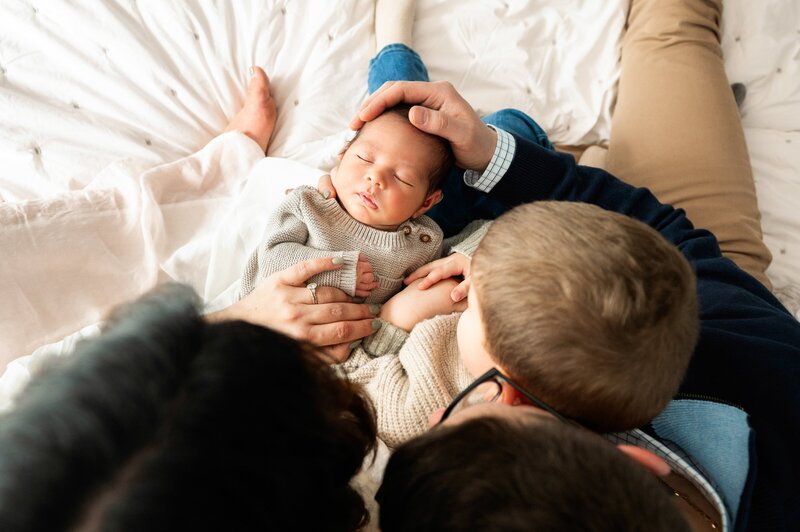 family of 3 holding newborn sister