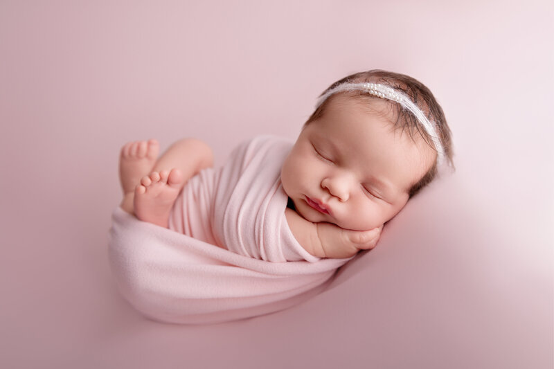 Fine-art newborn portrait of a baby girl gently wrapped in pink – captured in Paris, Ontario.