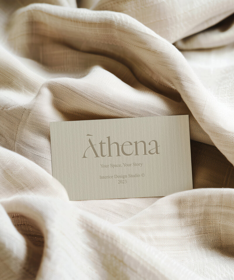 Athena brand identity with minimalist business card design for interior design studio, styled on neutral textured fabric.