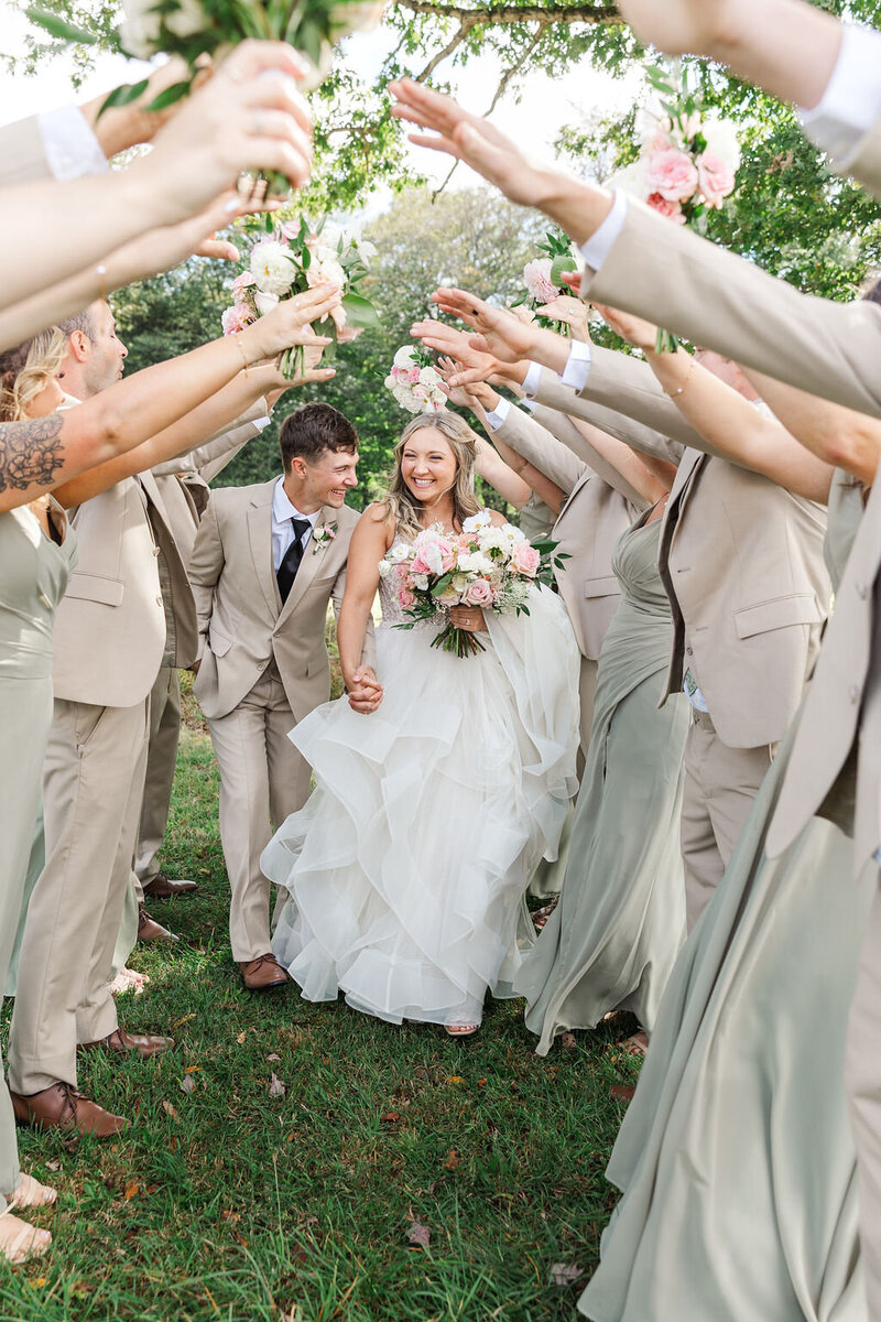 Photo of Bride and Groom walking through their wedding party at Tuck'd Inn Farm in Cooksburg PA