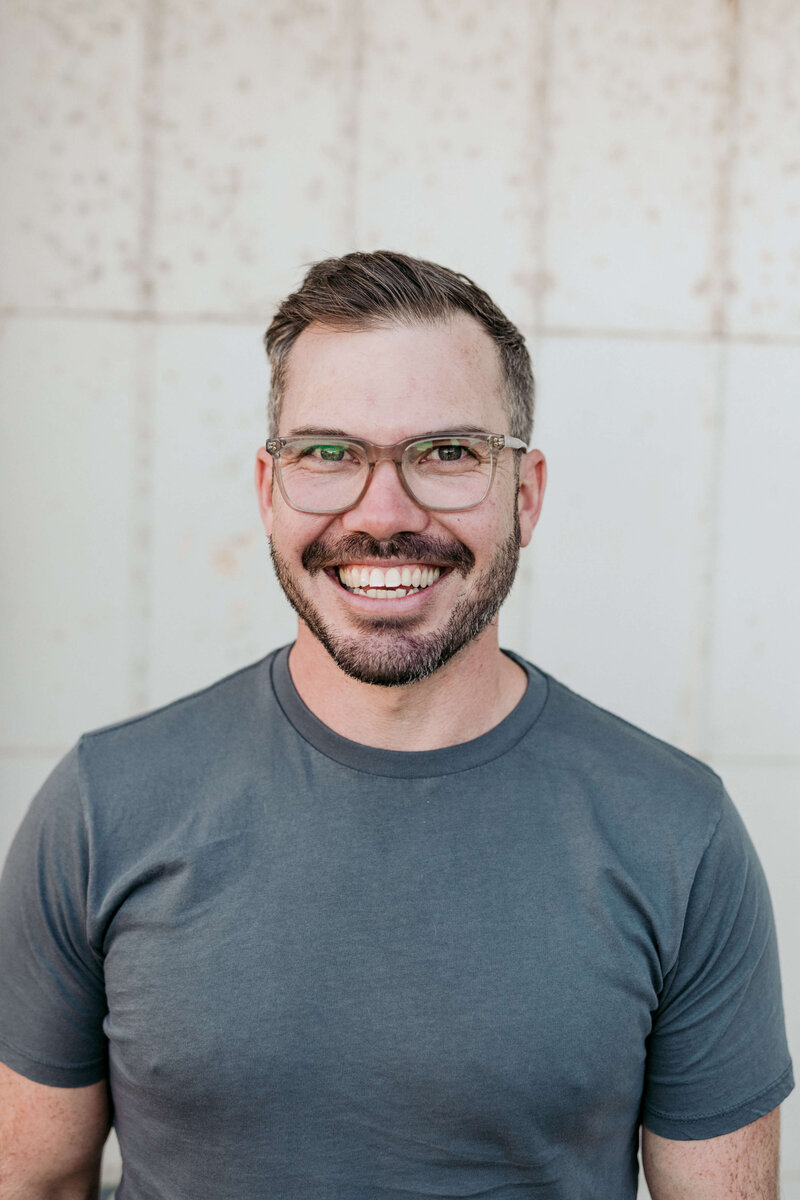 Luke, Adelaide wedding photographer, in a three-quarter portrait wearing glasses and facing the camera.