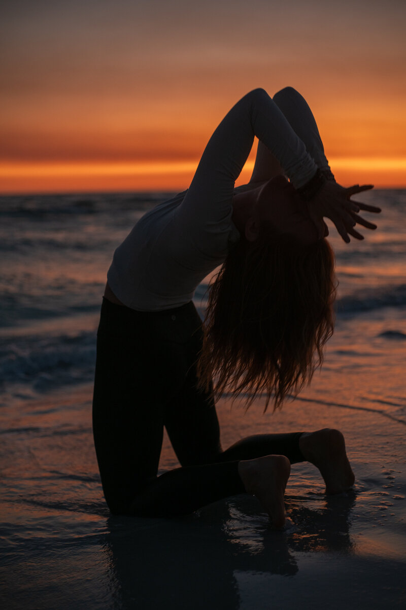 Stephanie in camel pose on the beach at sunset