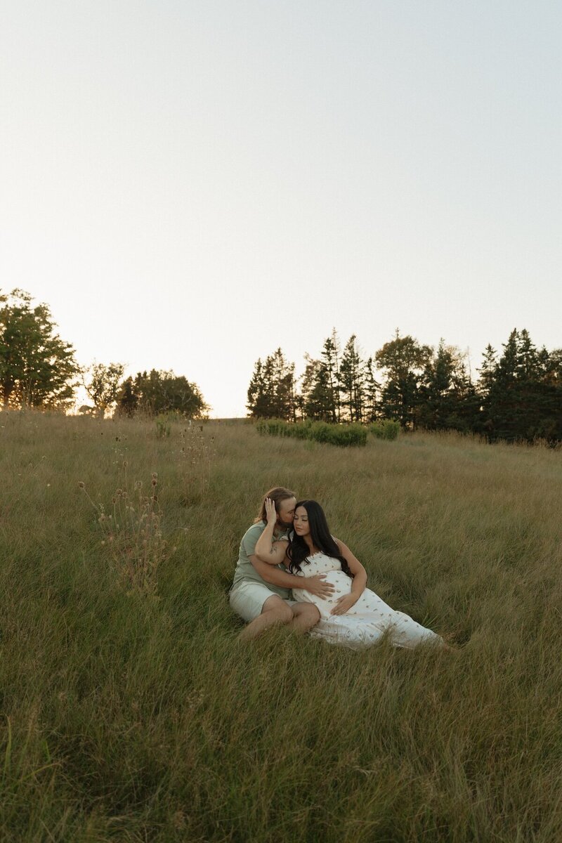 couple embracing in field for maternity session