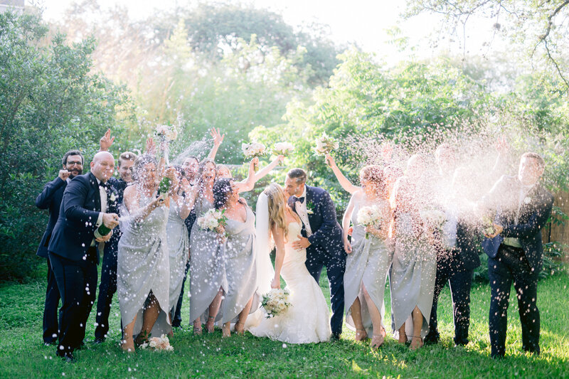 wedding guests pop champagne over bride and groom