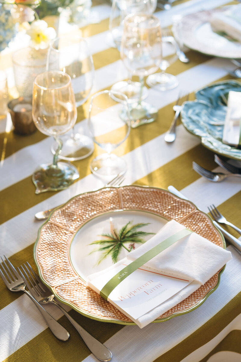 Closeup of dinner plate with napkin tucked in on striped tablecloth