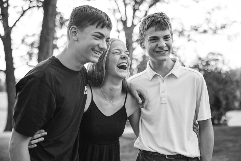 Teenage siblings hugging and laughing. 