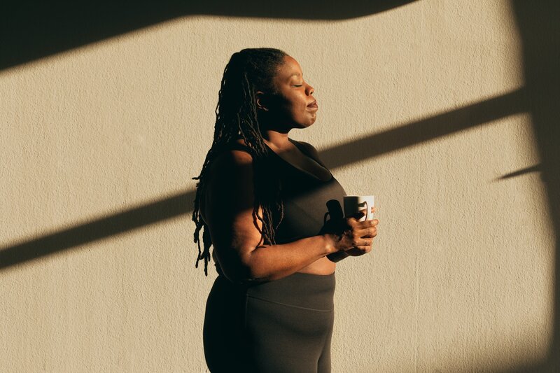 Woman Drinking Coffee Standing in Sunlight