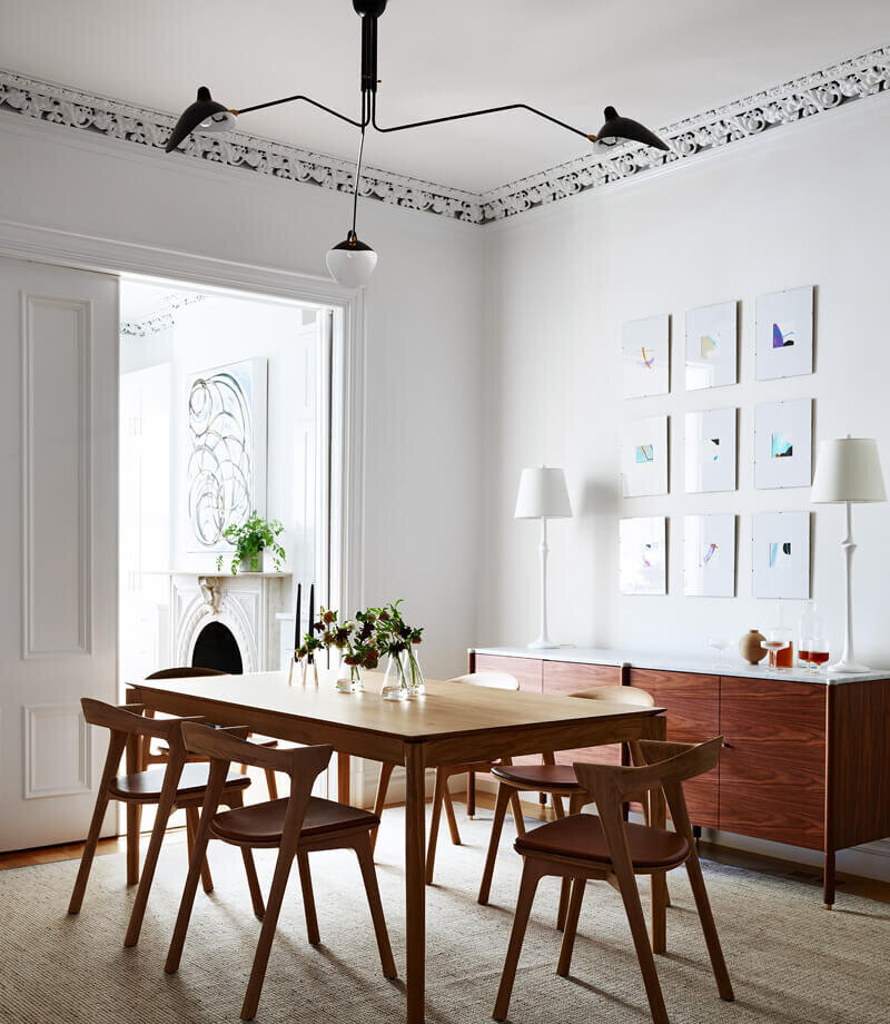 Interior decorators in Boston create a modern dining room in a historic brownstone, blending classic details with contemporary style by Sarah Scales Design.