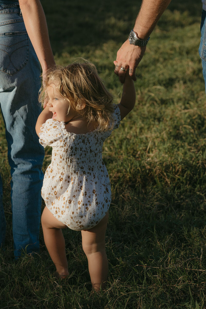 Styled Maui family photography session on a cliffside, capturing play and connection in denim and neutral tones.