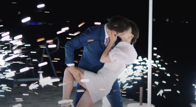 Bride and groom share a passionate kiss during nighttime wedding celebration with sparkling lights and fireworks — captured in a dramatic and emotional wedding video on the coast of Montenegro