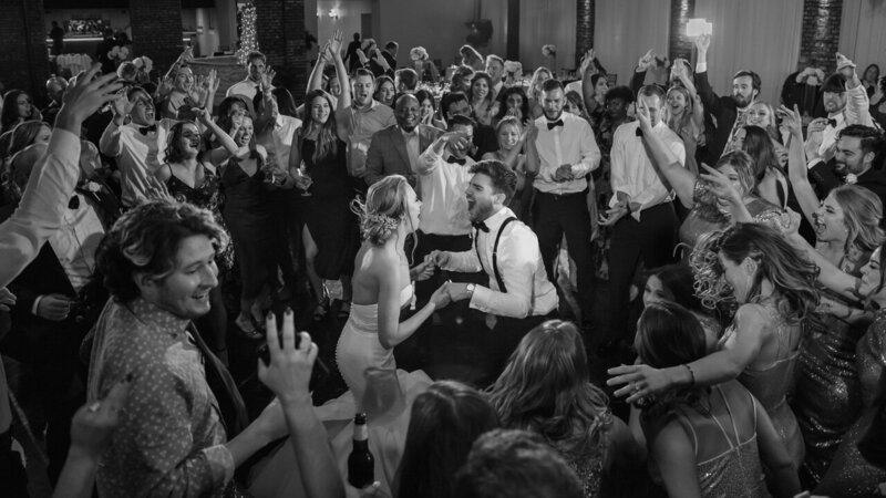 Bride and groom dancing up a storm at their wedding reception, surrounded by 50 guests, captured in a photojournalistic style.