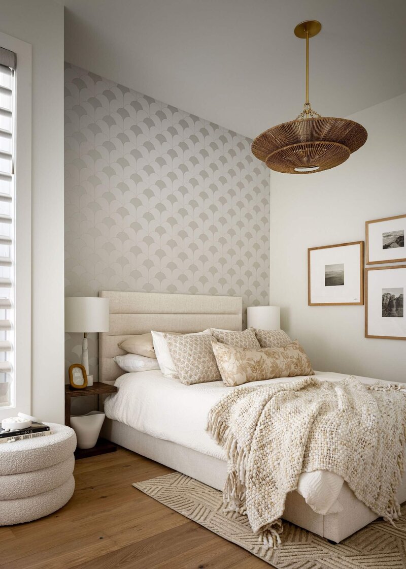 A light and airy guest room with a geometric metallic wallpaper, natural linens and a boho light fixture. 