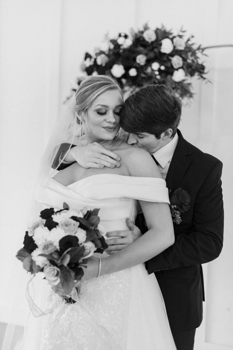Emotional moment as bride and groom kiss in front of round arch with florals at Tennessee mountain wedding
