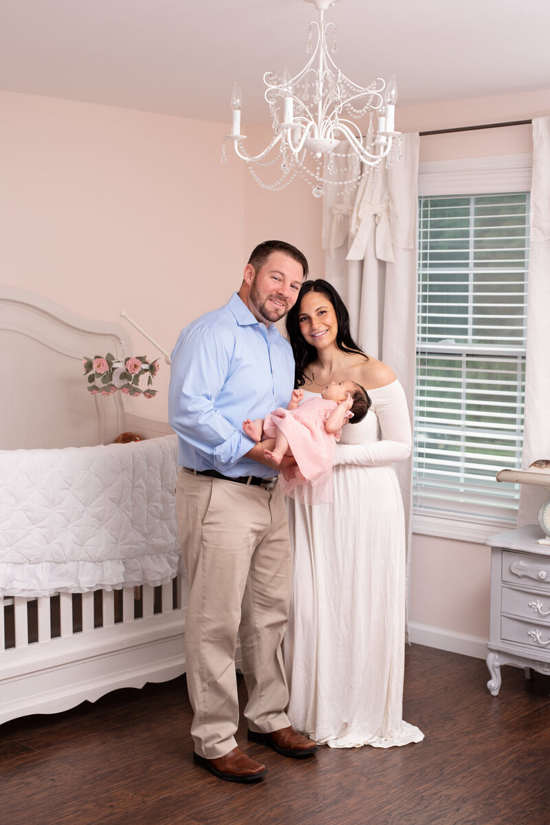 A couple holding their newborn baby girl in her nursey.