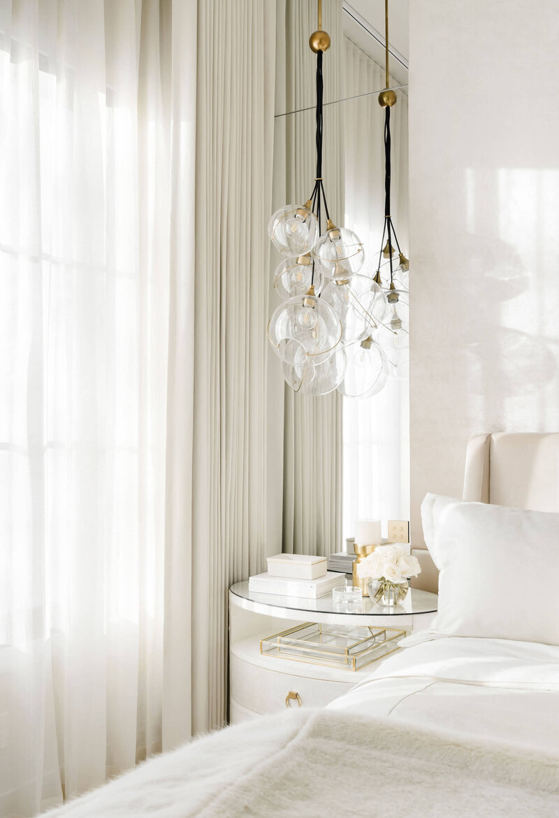 Clustered pendant paired with oval hide nightstands and hotel bedding. 