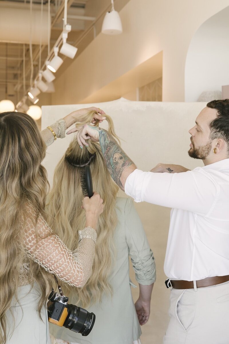 Two hairstylists taking photos of hair extensions