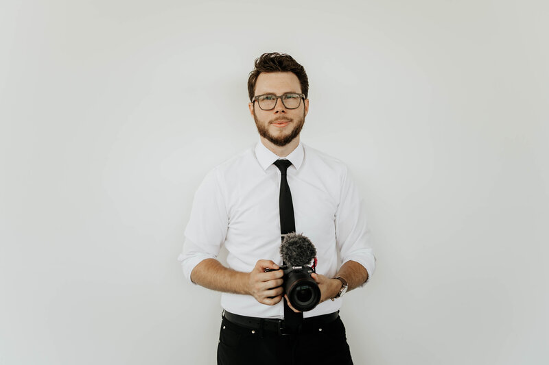 Wedding videographer holds camera and smiles