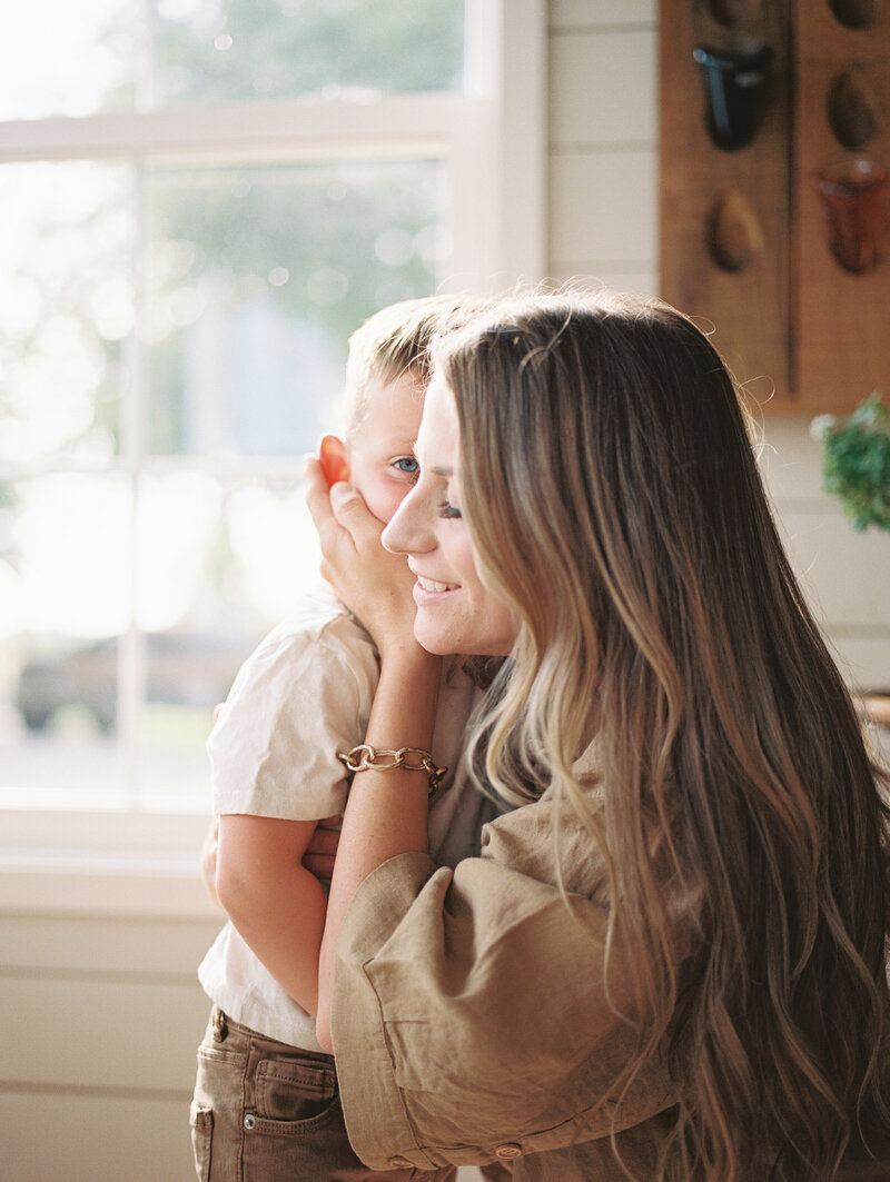 Little boy kissing his mom on the cheek while she holds his face