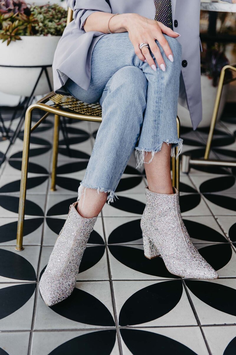 Close Up of Woman Sitting with Legs Crossed Wearing Denim Jeans and Sparkly Boots