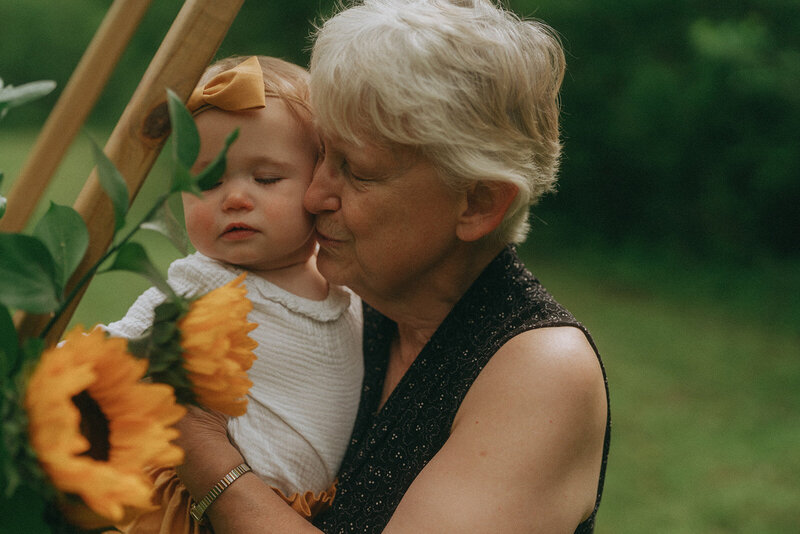 grandmother holding baby with flowers during family photos by NYC family photographer Elsie Goodman