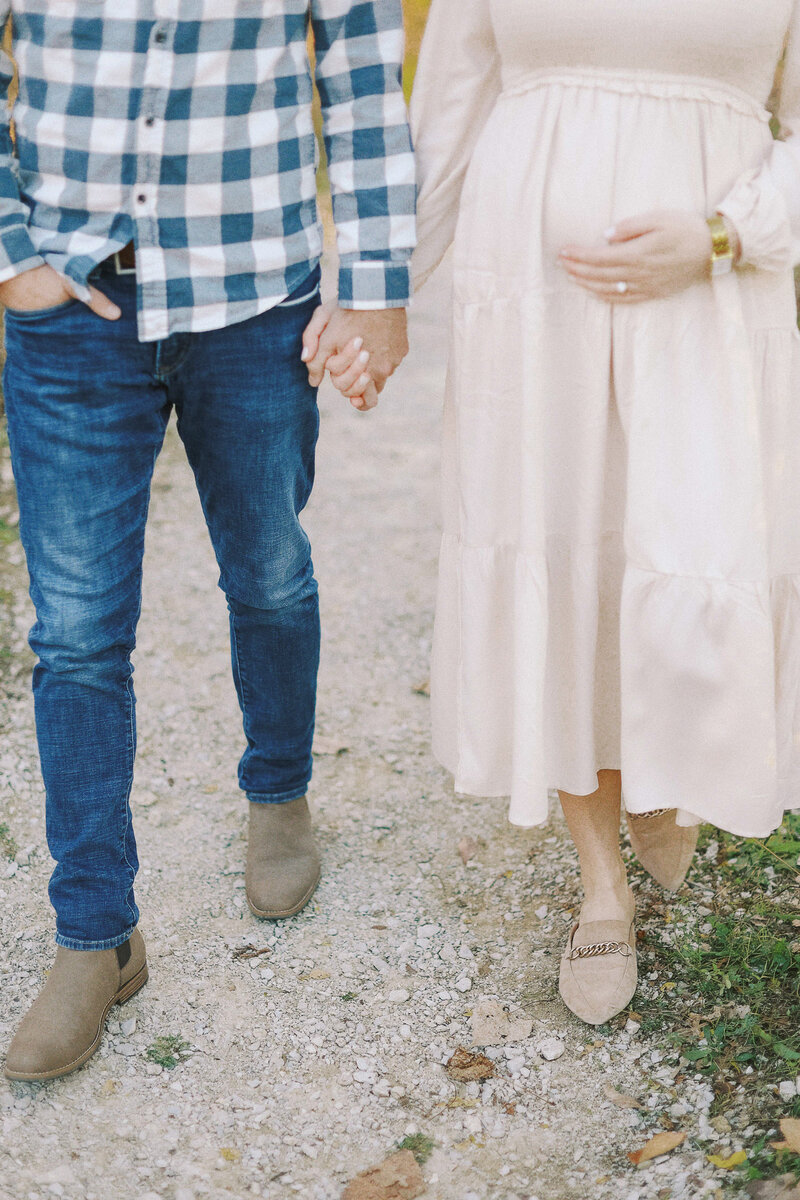 close up of a man walking while holding hands with his pregnant wife
