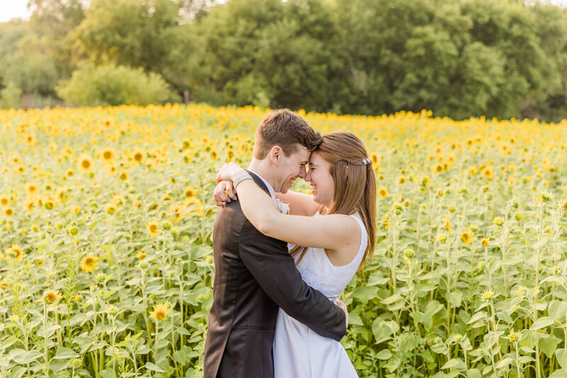 Bride and groom in sunflower field at golden hour.
