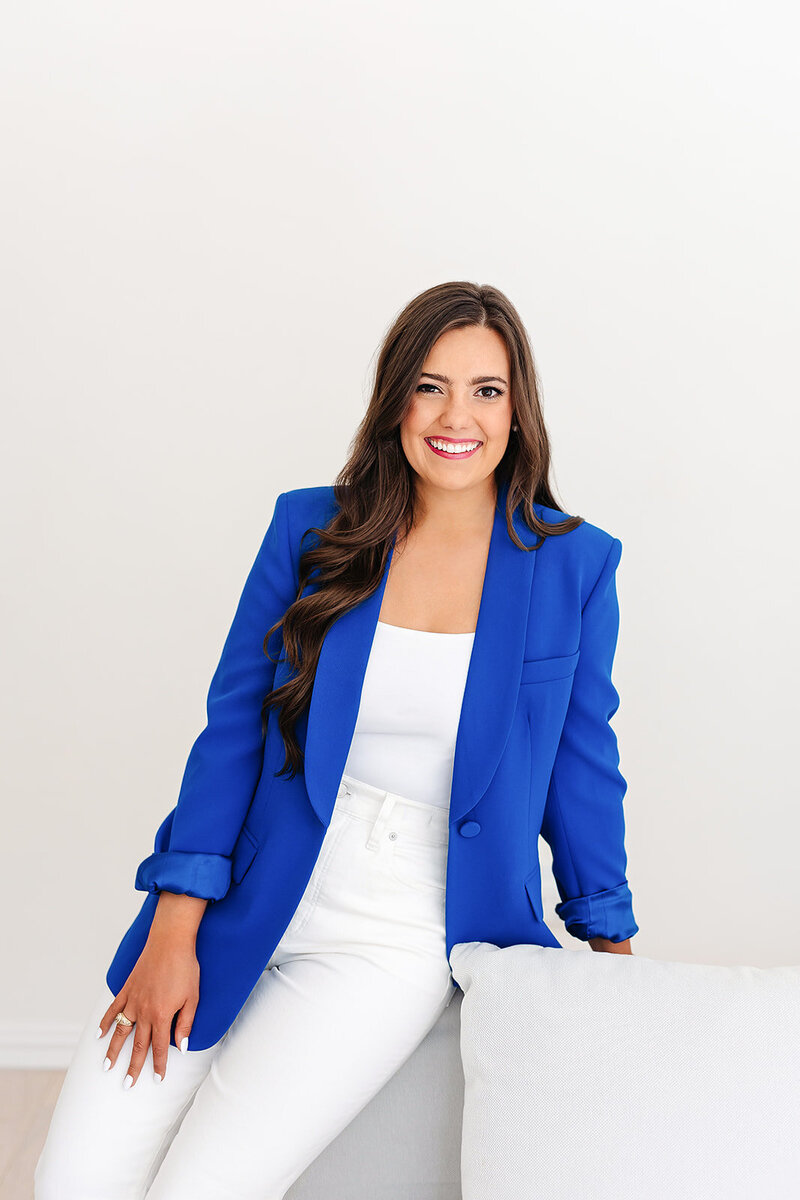 Headshot of Abby Manawes in a white outfit and bright blue blazer