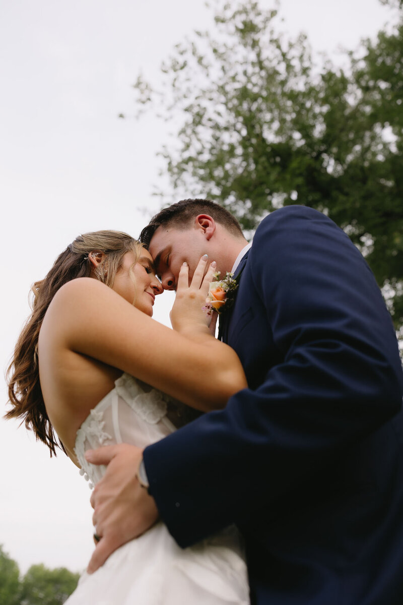 Bride and groom touching foreheads outdoors