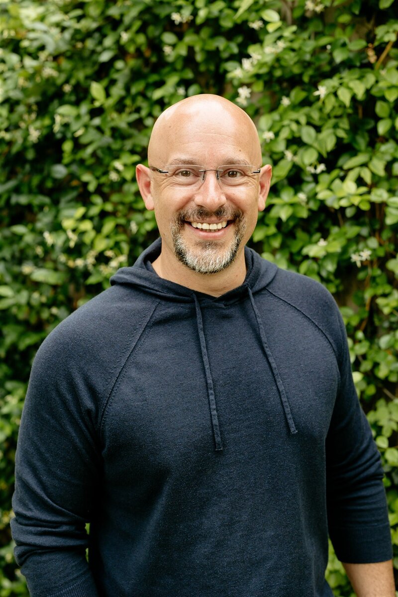 Sam Jacobson, sales and pricing expert for wedding pros, smiling in front of hedge.