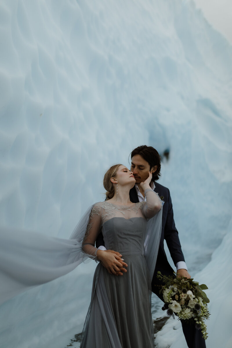 bride and groom standing on glacier