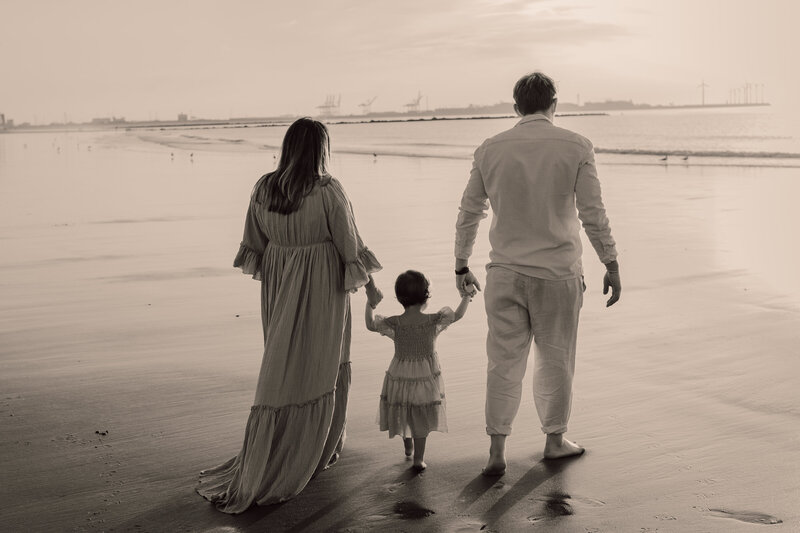 Gezin wandelt samen op het strand, hand in hand tijdens familie fotoshoot in Knokke.