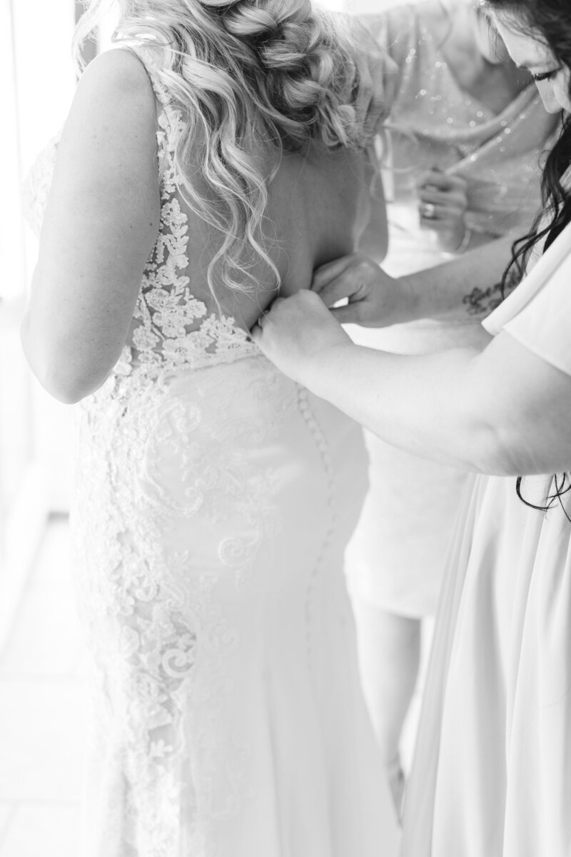 maid of honor zipping up the bride's dress in black and white