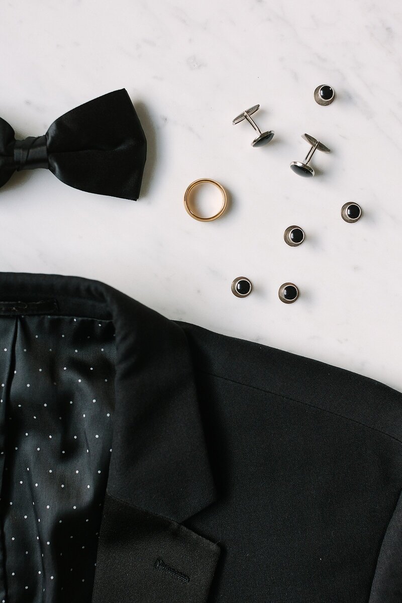 detail photo of groom's details black jacket bow tie cufflinks gold ring
