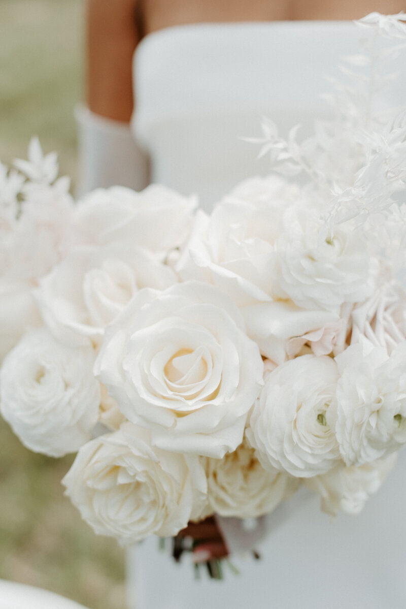 Bride Jenay holding a bridal bouquet with white blooms and ruffled garden roses in mauve and sand tones, designed by Summer Robbins Flowers in Central Oregon