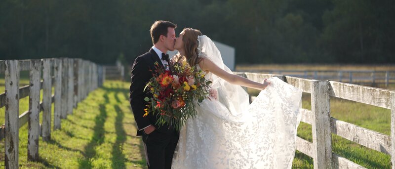 bride and groom walking through a field smiling at each other while holding hands