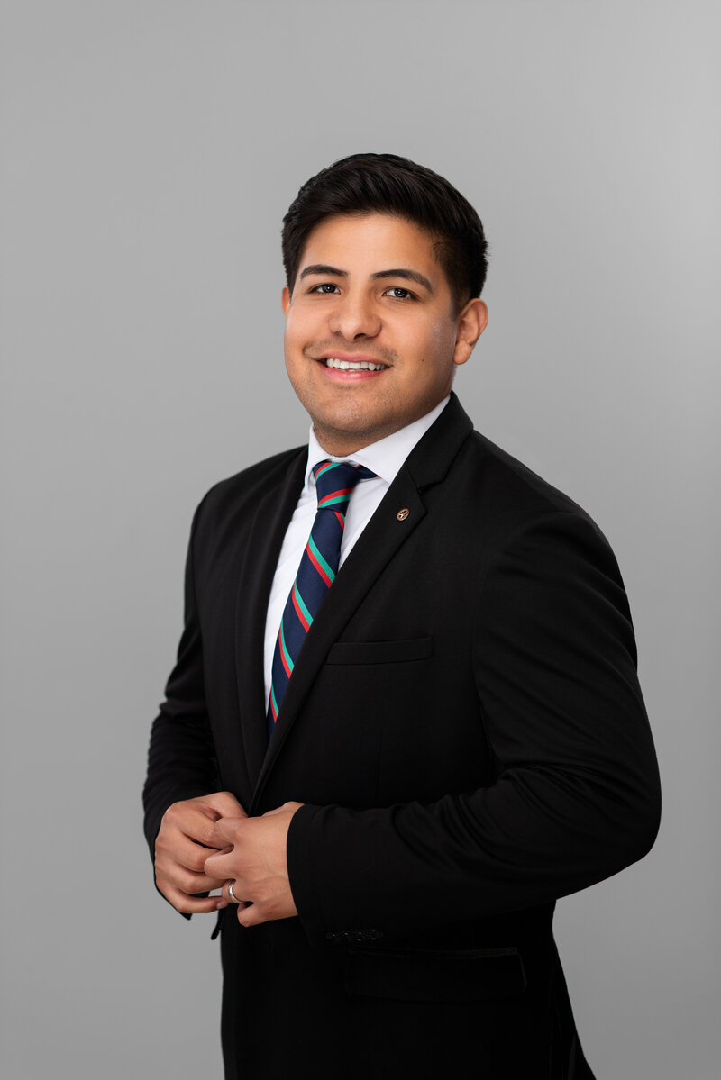 Young banker in a suit and tie smiles for his headshot