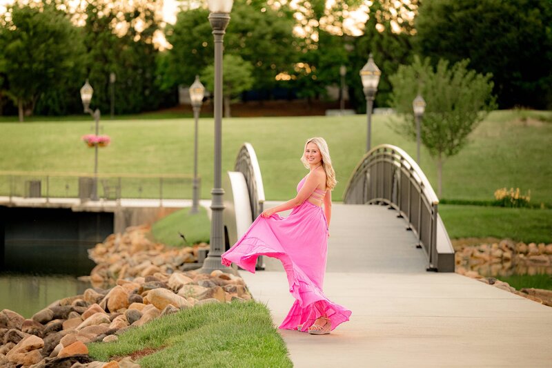 movement photo of a grad twirling her long pink dress during her senior photos in indian land, sc