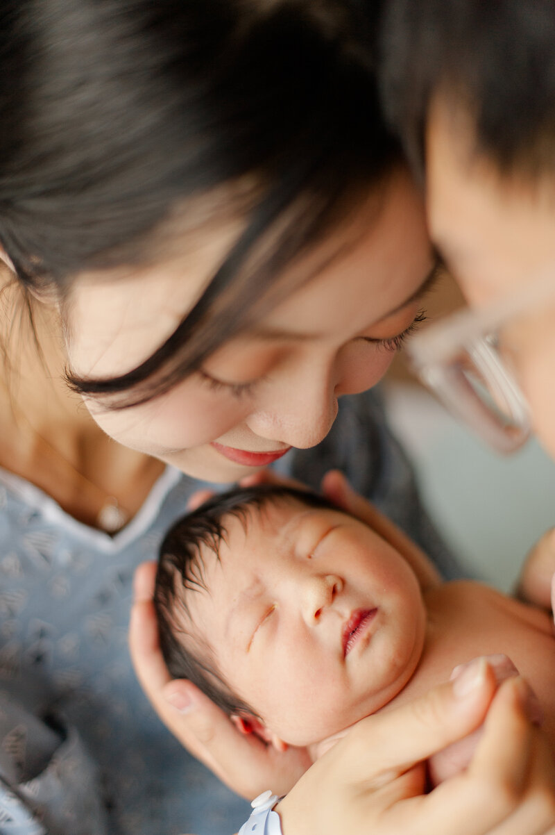 Closeup of parents holding newborn baby in the hospital hours after birth