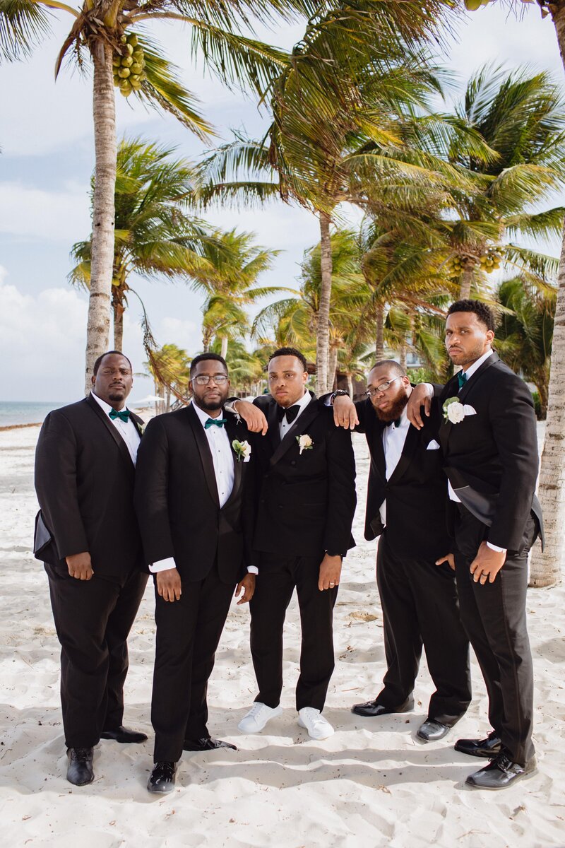 A group of groomsmen posing on the beach.