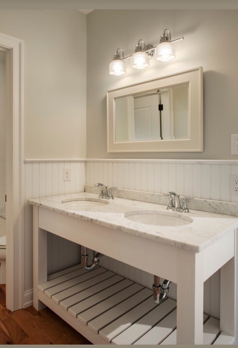 A clean, neutral modern farmhouse bathroom vanity featuring double sinks, and beadboard accents